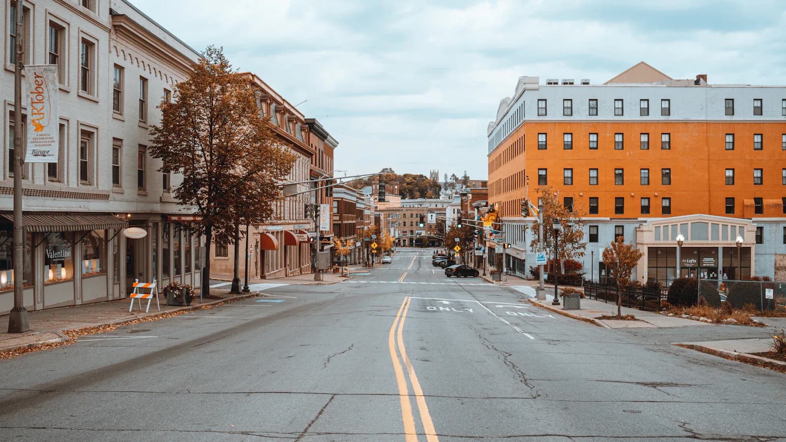 Downtown Bangor Maine main street with historic brick buildings and fall foliage on an overcast day