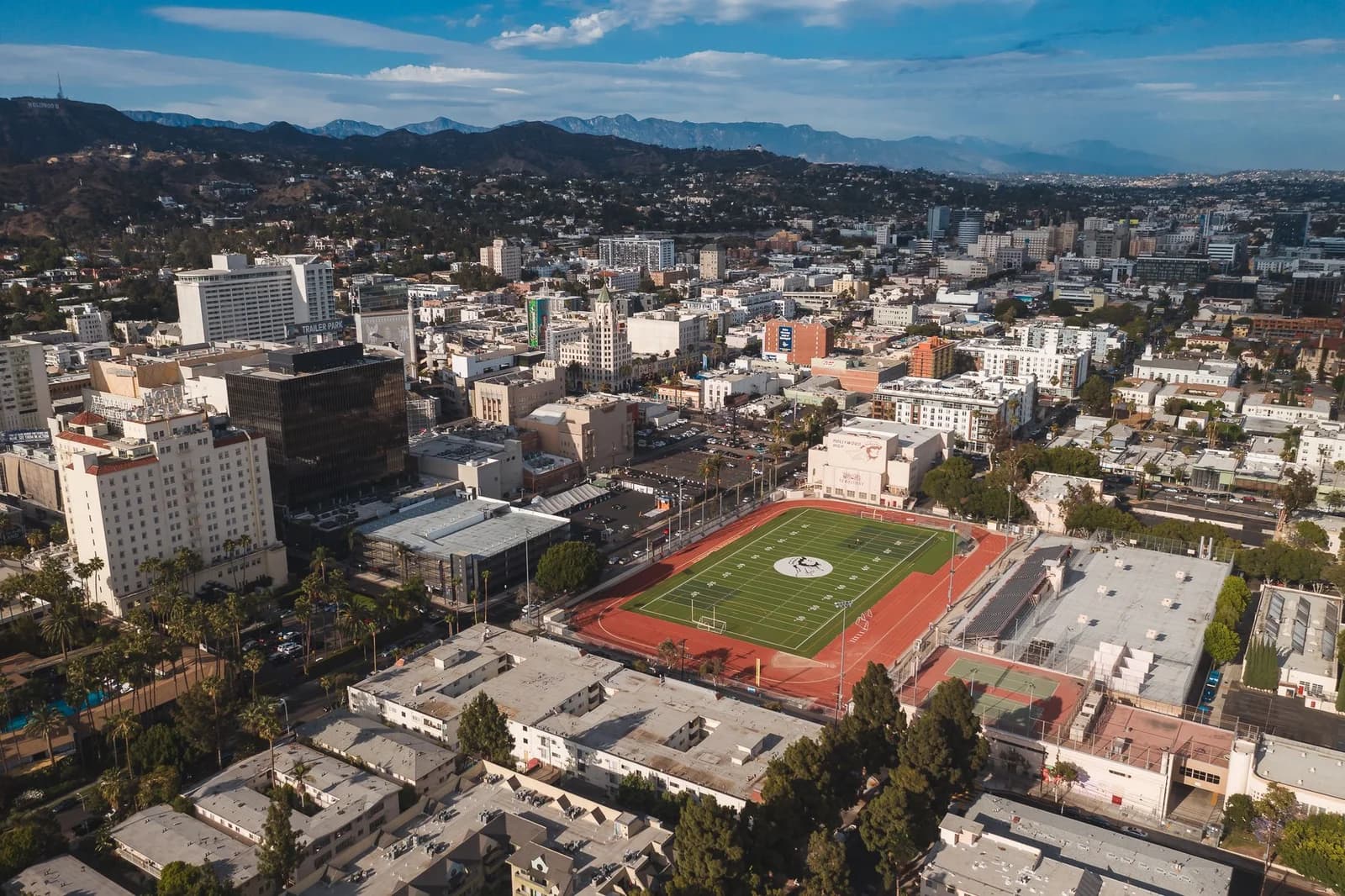 Stunning aerial view of Los Angeles cityscape featuring a prominent football field in the foreground.