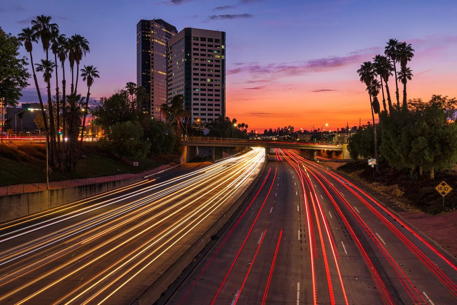 Vibrant sunset view of Burbank highway, palm trees, and light trails creating a dynamic urban scene.