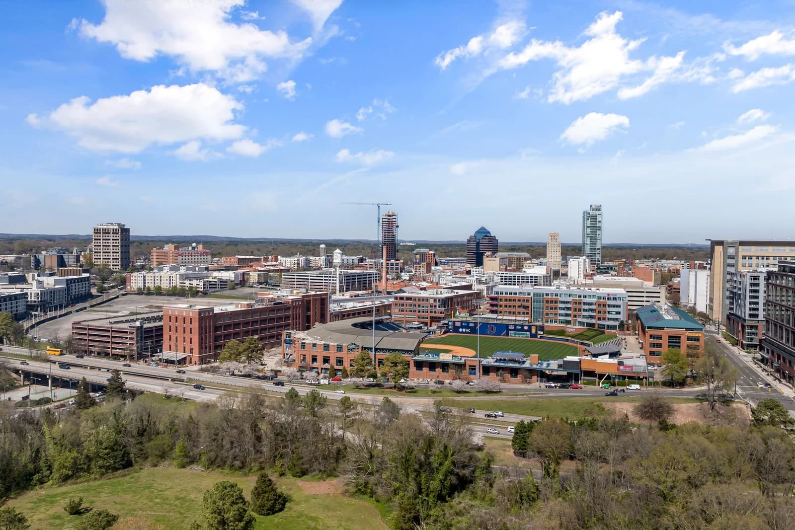 Aerial photo showing downtown Durham's vibrant skyline and cityscape on a sunny day.