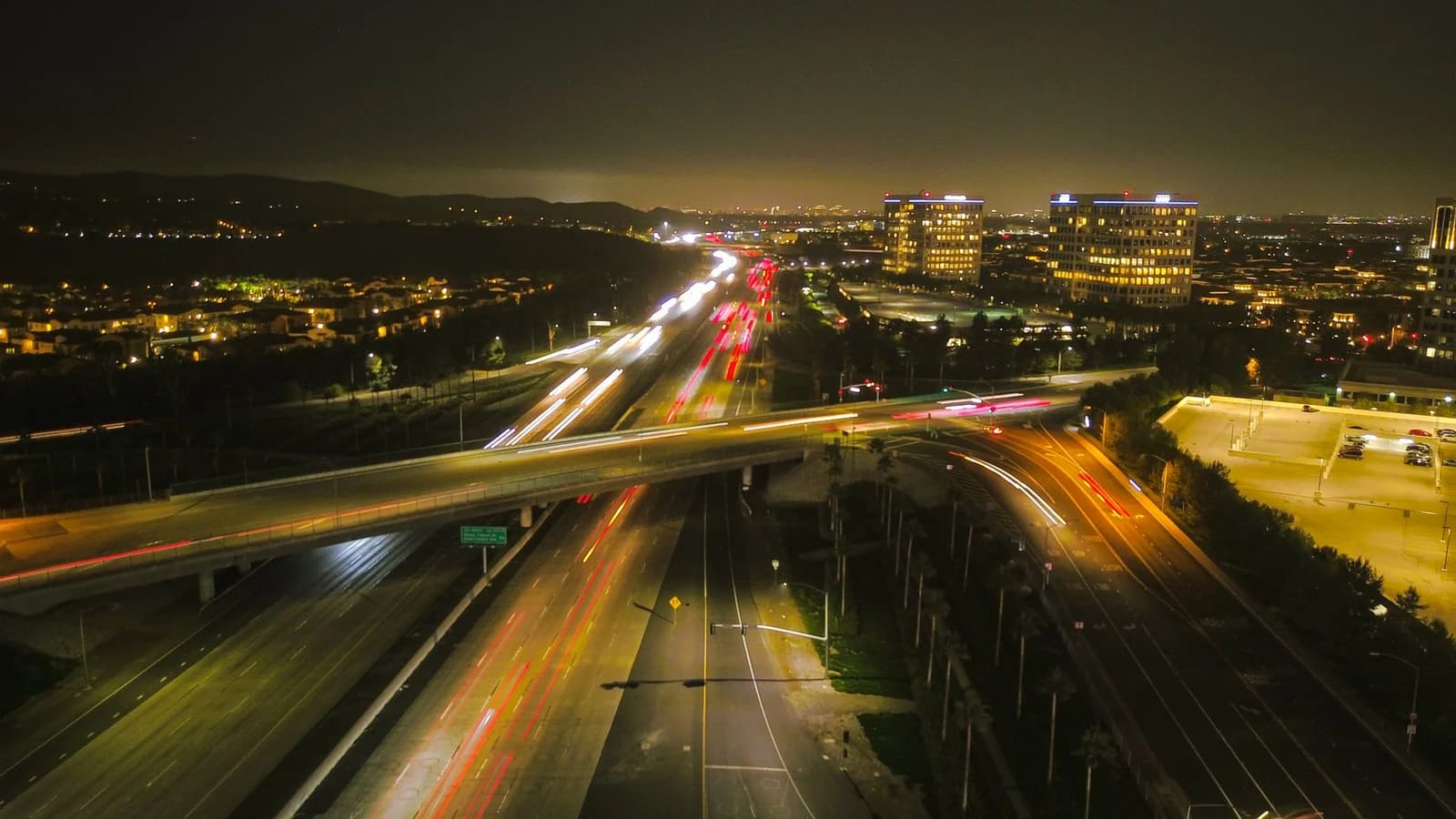 Aerial view of a bustling city highway at night, showcasing vibrant lights and urban architecture.