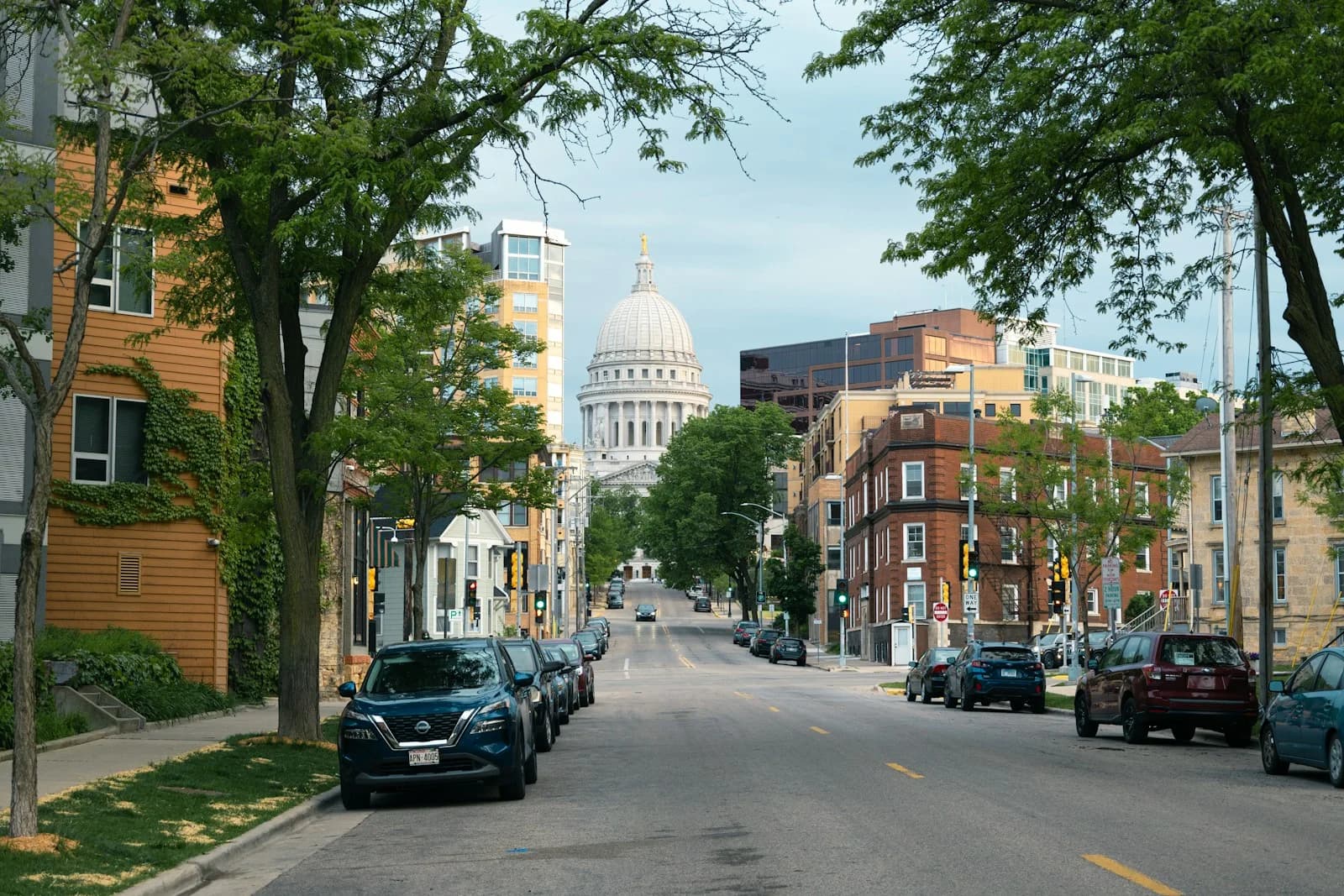 The Wisconsin State Capitol dome at the end of a tree-lined street in downtown Madison