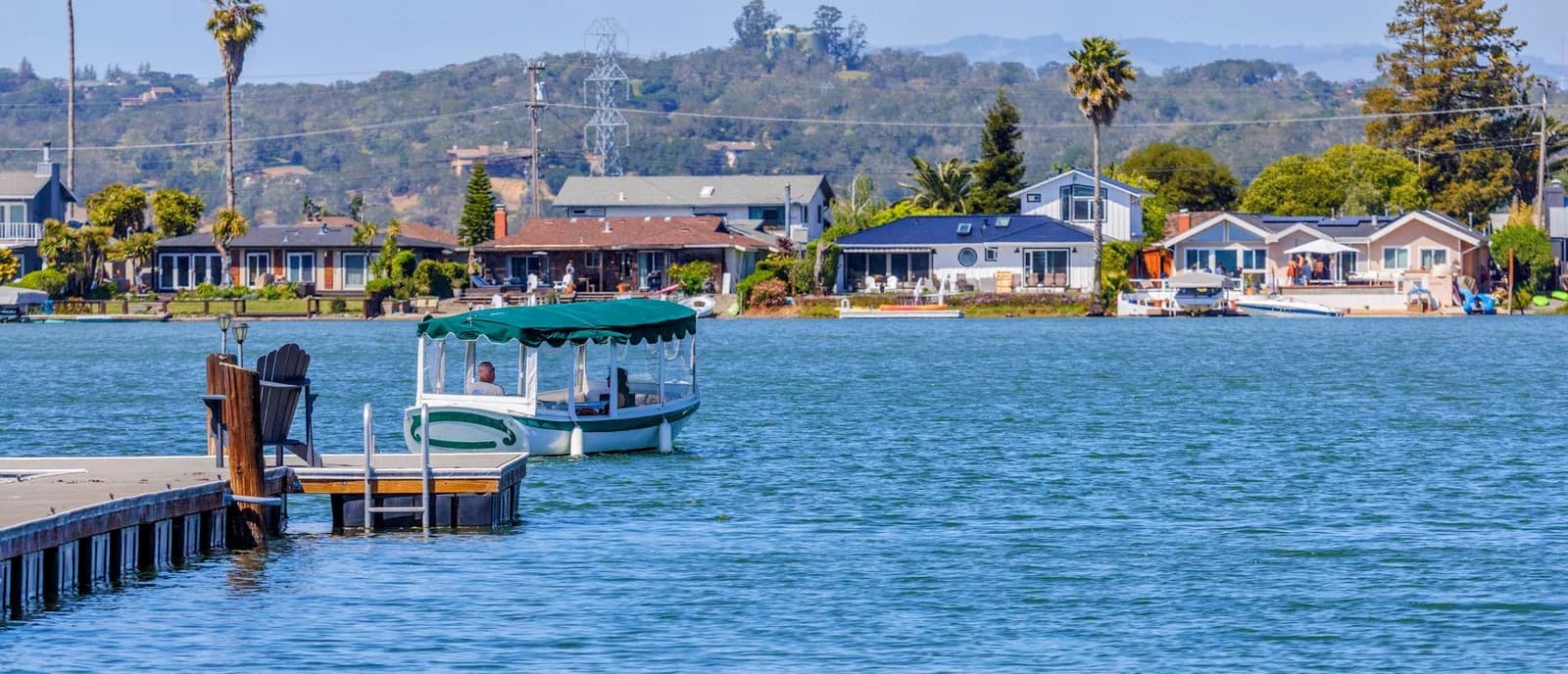 Serene lakeside village featuring homes, pier, and boat on a sunny day.