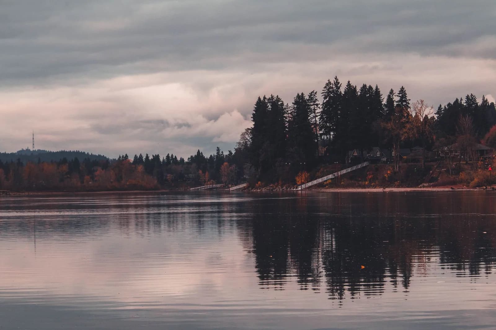 Tranquil reflection of trees on calm water under a cloudy sky in West Linn, Oregon.